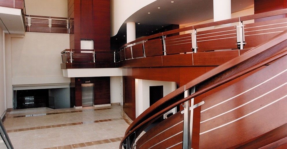 L’atrium de Bombardier : mezzanine courbe et garde-corps de bois sombre, accueil encastré dans un mur de panneaux