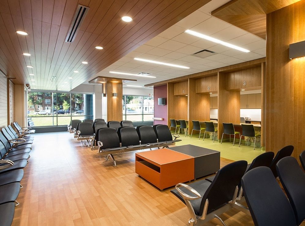 La salle d'attente de l'Hôpital Shriners pour enfants à Montréal : plafond de bois, cloisons de bois, sièges et fenêtres sur la rue