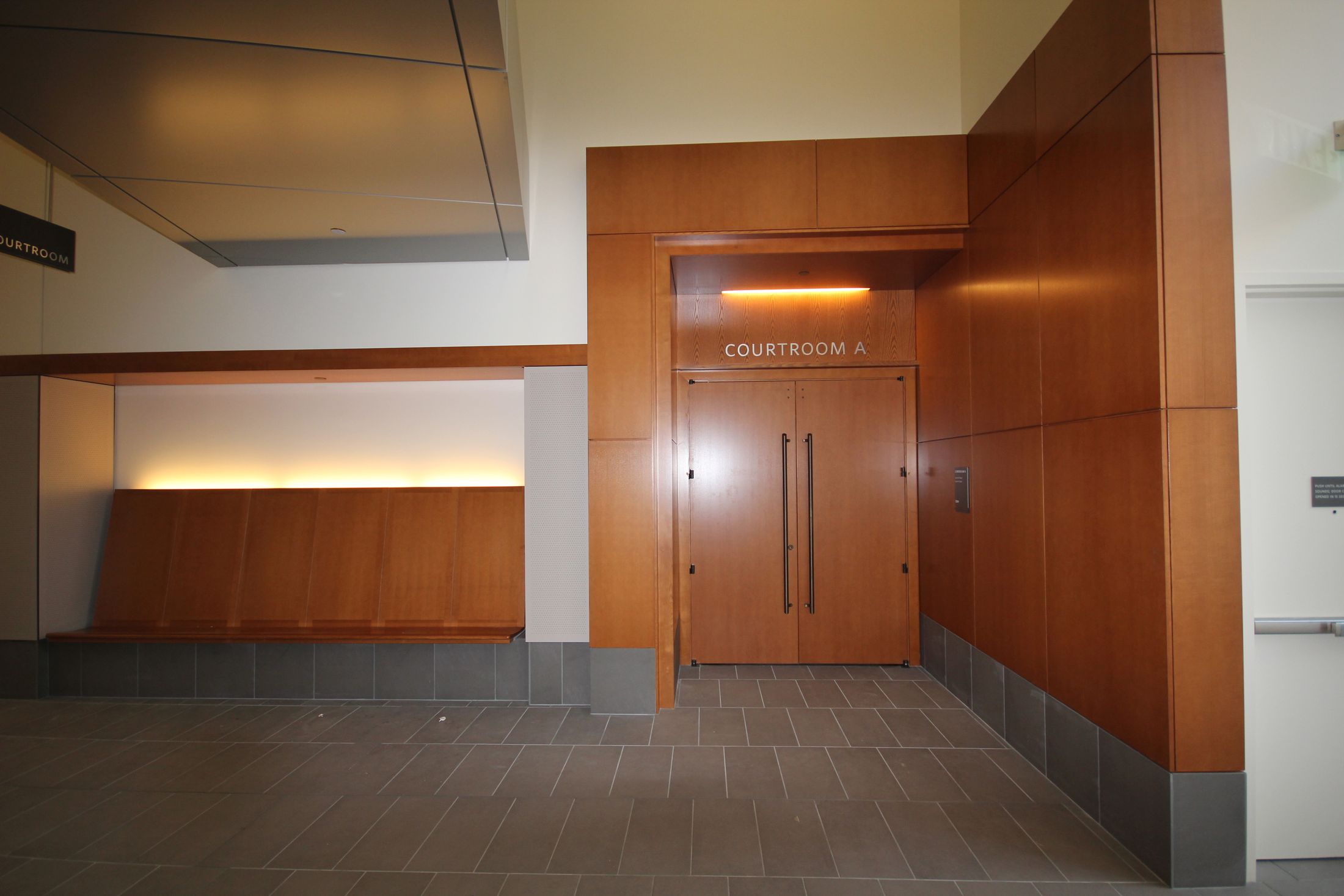 L'entrée de la salle d'audience A du palais de justice de Springfield : lambris et portes de bois, éclairage indirect